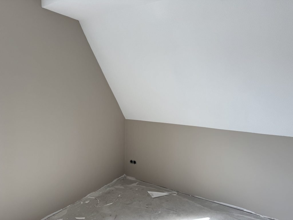 Zolderkamer met een schuine wand en rechte muren die zijn afgewerkt