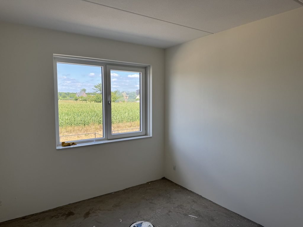 Lege kamer met lichte wanden waar het daglicht via het raam langs de muur valt