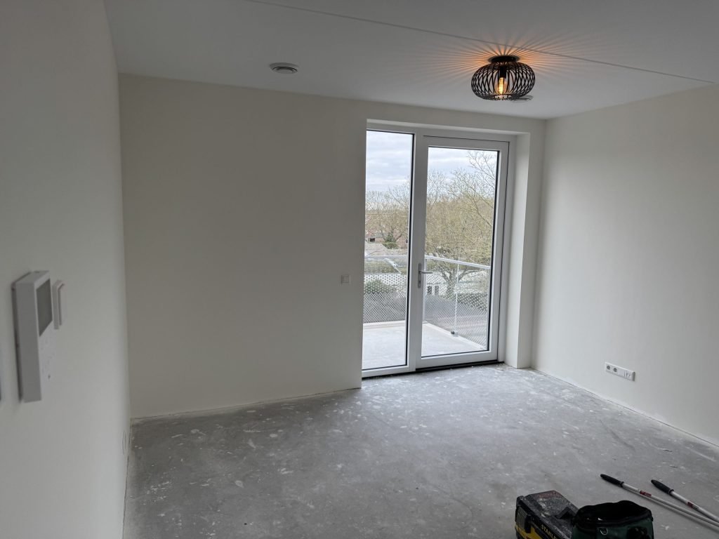 Lege kamer met openslaande deuren en kale wanden voor de afwerking